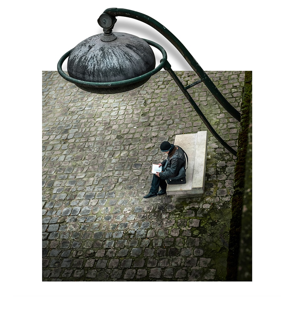 A compelling study in contrast, this image juxtaposes the grand scale of urban architecture with the solitary figure of a person. The oversized streetlamp looms protectively over the lone individual, creating a sense of both isolation and shelter. This piece invites contemplation on the nature of city life and our place within it.